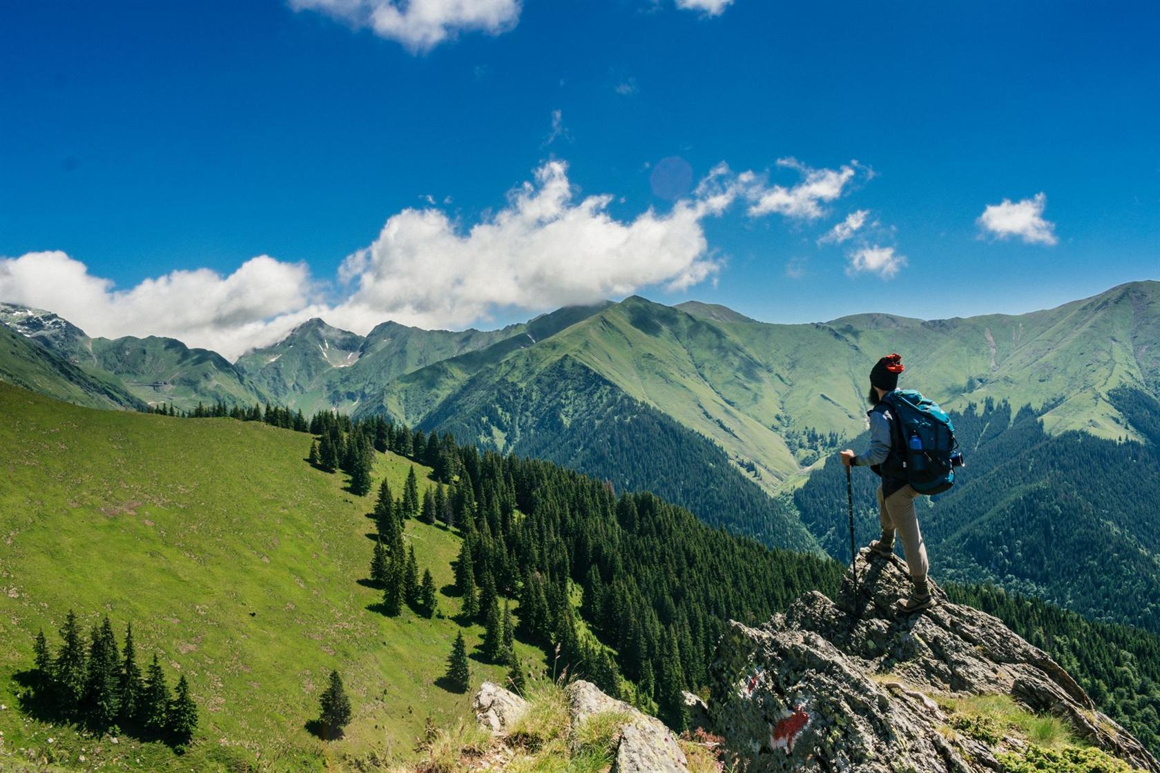 Randonneur face à des montagnes verdoyantes